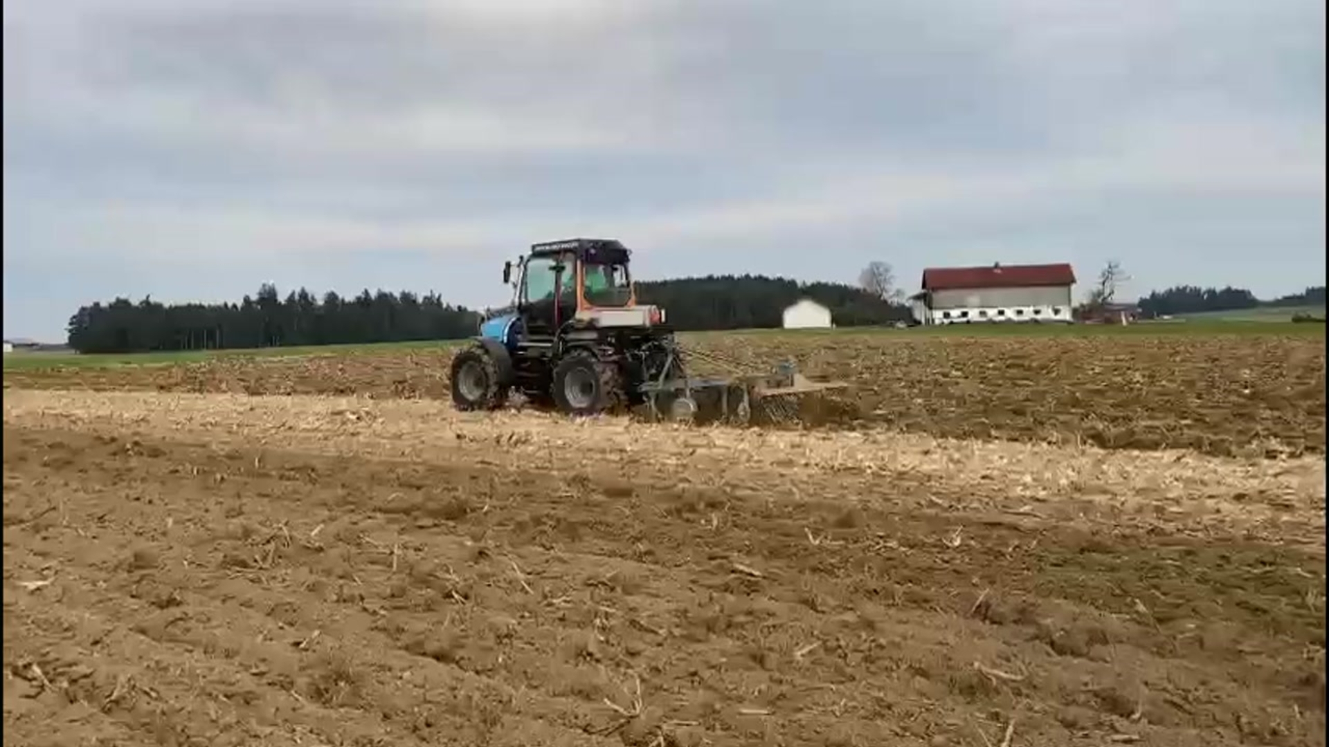 Zu sehen ist der elektrische Erprobungstraktor von TADUS beim Grubbern auf einem Acker.